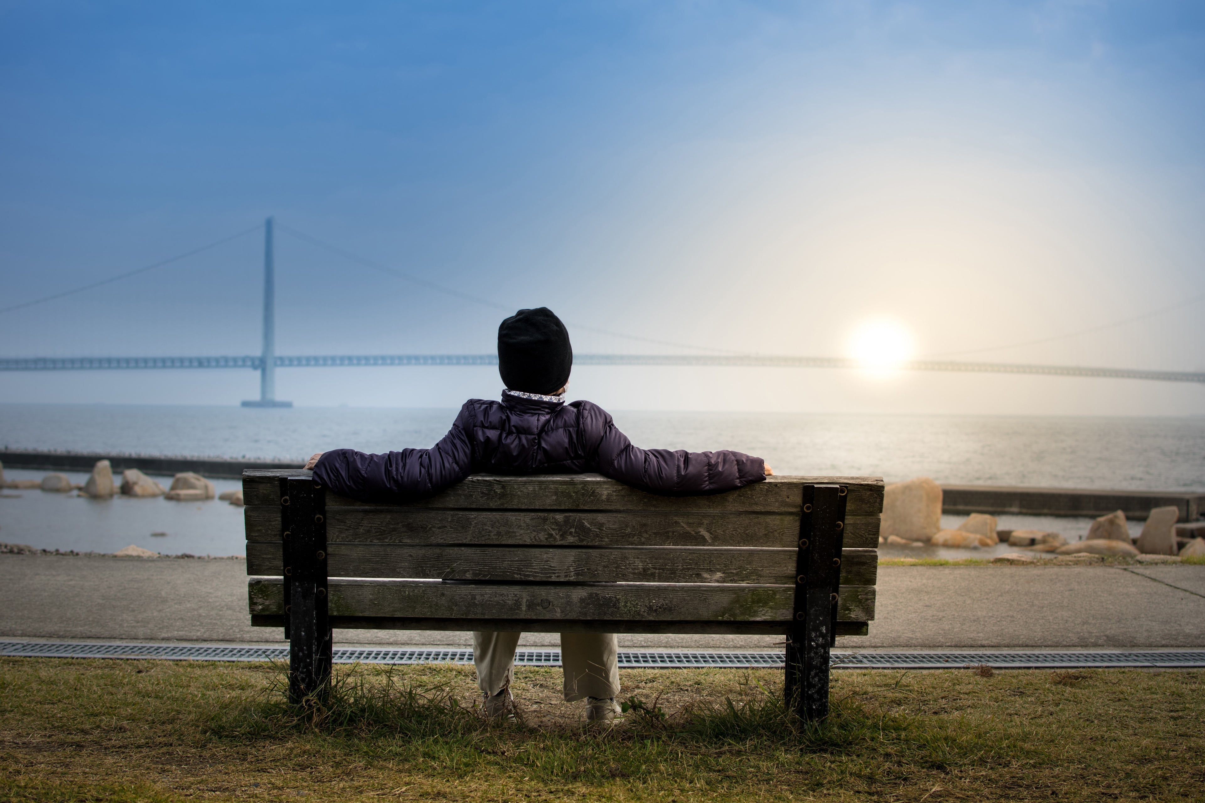 Person sitting on a bench by a waterfront with a bridge in the background after taking terp&twist